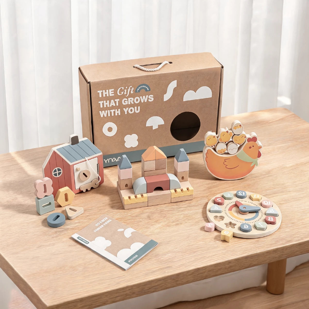 Wooden educational toy set with barn, castle, chicken, alphabet blocks, clock, and booklet, box says "The Gift That Grows With You"