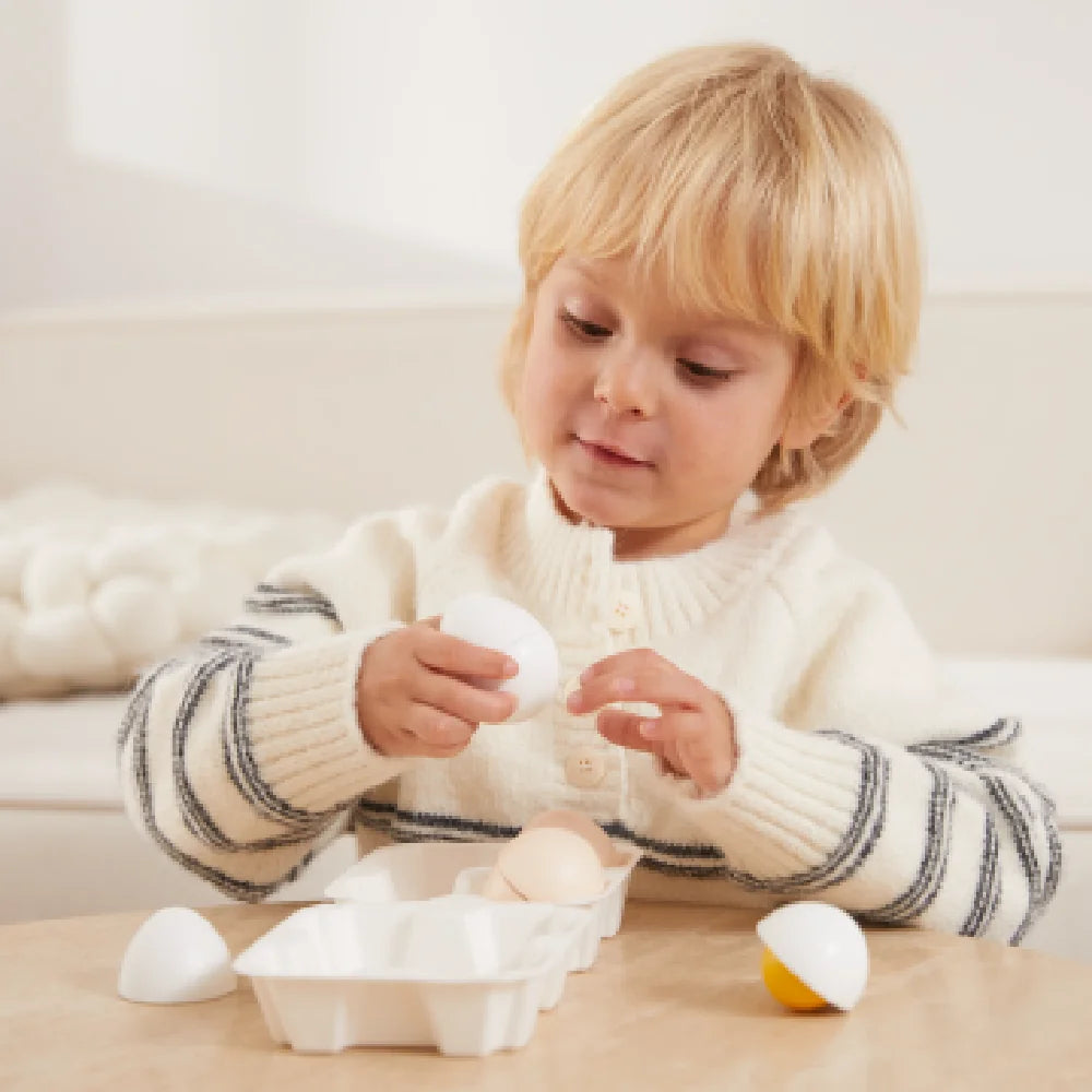 Toddler playing with egg-shaped educational toys on a table.