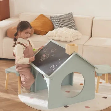 Child plays at wooden house chalkboard desk with stool, by couch.