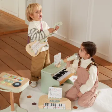 Two children playing with wooden musical toys including a guitar, piano, and keyboard on a rug.