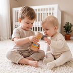 The Discoverer Growing Play Box - older sibling showing the rainmaker rattle to a baby