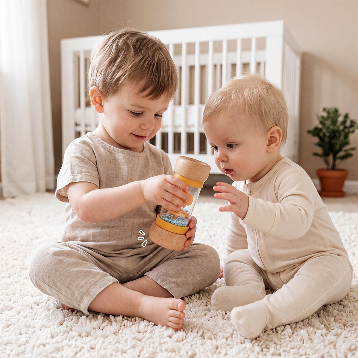 The Discoverer Growing Play Box - older sibling showing the rainmaker rattle to a baby