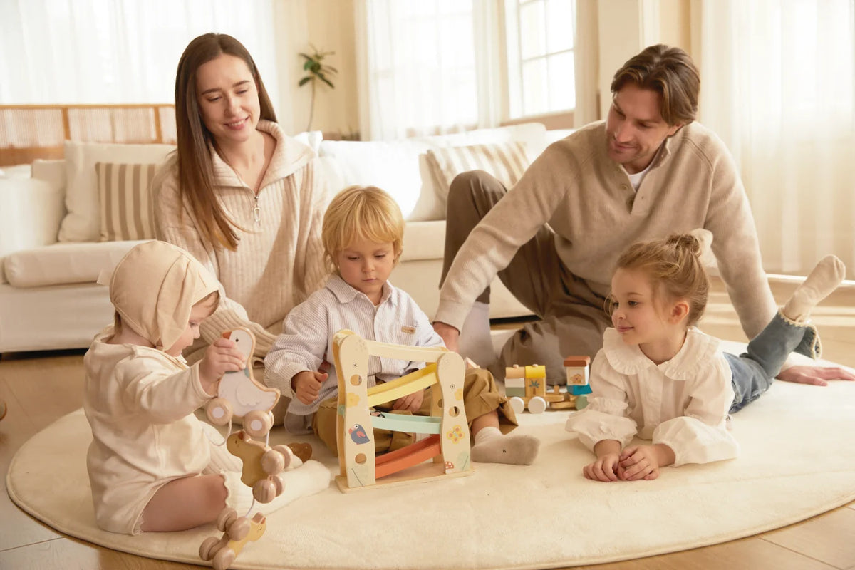 Family with children playing on a rug with wooden educational toys
