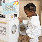 Young boy plays with Freniland wooden toy washing machine labeled Wash Clothes