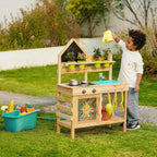 Wooden outdoor play kitchen with child watering plants from yellow can.