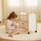 Young girl playing with a wooden toy doll crib and baby doll