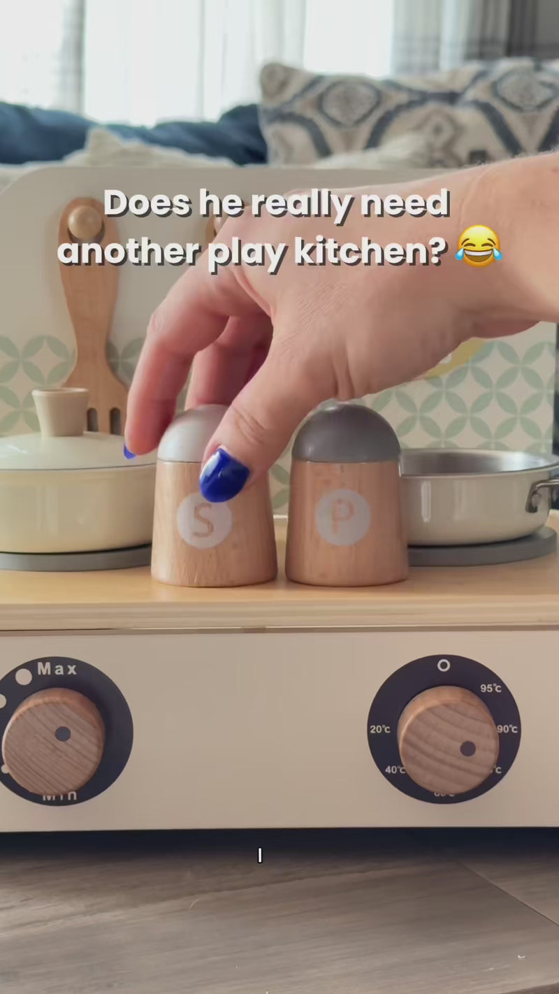 Hand touches wooden toy stove with salt and pepper shakers by Freniland.; Child playing with wooden educational kitchen toy featuring pots and pans